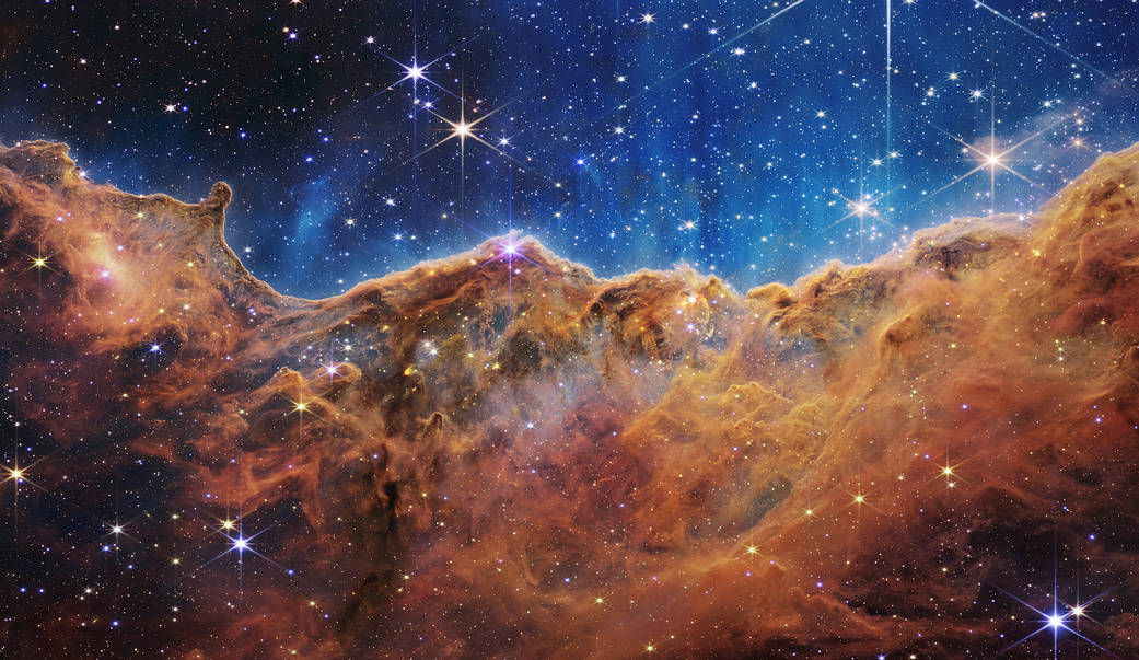 An image of cosmic cliffs in the Carina Nebula, taken by NASAs James Webb Space Telescope. With more and more technologies pushing the limits of space exploration, two Harker Aquila writers argue for the pros and cons of exploring our universe. 
