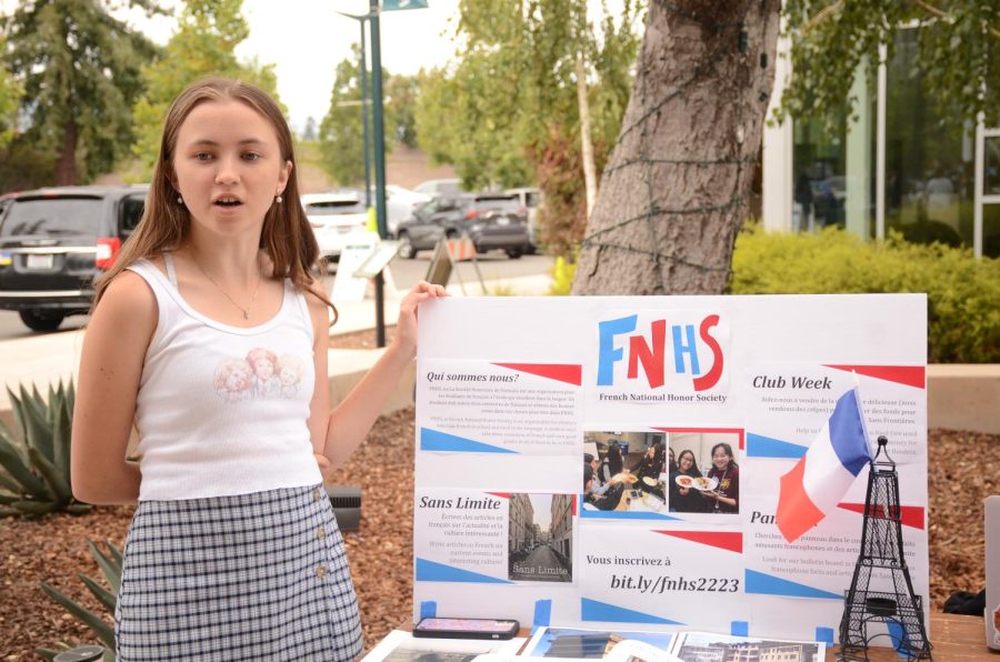 Anja Ree (12) presents the French National Honor Society (FNHS) poster board to students at Club Fair. The event featured over 70 clubs, allowing students to learn about various student-run organizations at the upper school.