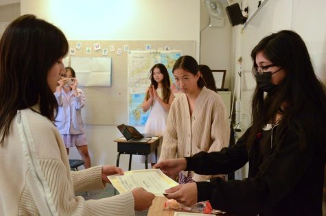 JNHS co-Vice President Maryam Zehra (11) hands a membership certificate to Bella Chen (10) at the induction ceremony on Oct. 17. Each new member of the organization received a certificate after taking an oath to serve the community through JNHS.
