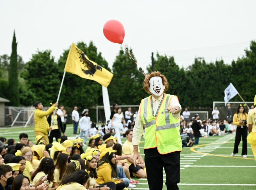 Senior class dean and upper school production manager Brian Larsen holds out a red balloon, dressed up in a Pennywise the clown costume. The seniors theme for Spirit week was IT.