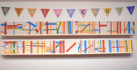 Student creations sit on a wall in the Rothschild Performing Arts Center. “[Stripe Club] creates a fun sense of community,” Christina Rex (11) said.“It almost gives [me] purpose when I get ready every morning. [I think], I know what color is gonna happen today, I can dress up for it.”