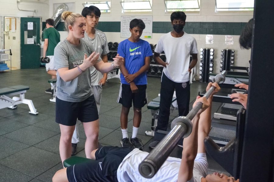Upper school Strength and Conditioning Coach Lauren Brown teaches proper bench press fundamentals to underclassmen during a workout session. Brown trains students in after school fitness classes and students from sports teams.