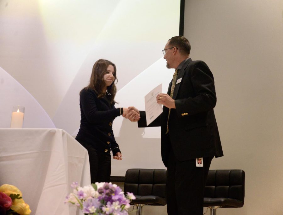 Ariana Goetting (11) receives her NHS certificate from NHS adviser Chris Davies. Altogether, NHS members accumulated 2,523 volunteer hours over the course of the year.