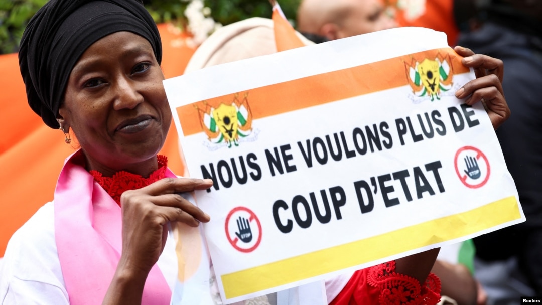 A Nigerien woman holds up a sign reading we dont want a coup anymore. A military junta overthrew President Mohamed Bazoum on July 26, making Niger the latest in a series of coups. (Provided by editorials.voa.gov)