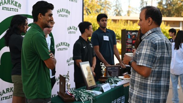 A parent converses with athletics department representative Vyom Vidyarthi (11) at the Harker athletics booth during Back-to-School Day on Saturday. Club and organization representatives, including faculty and students, set up booths outside the Rothschild Performing Arts Center (RPAC) Saturday morning.