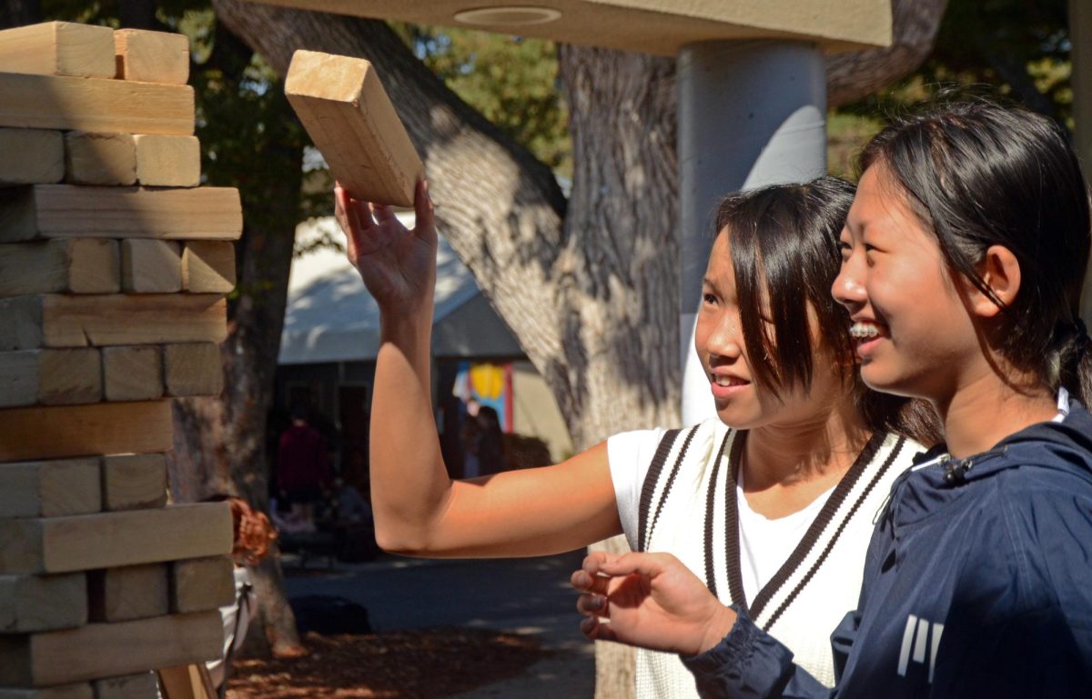Isabelle Niu (9) watches as Eliana Chui (9) stacks a wood block during a Jenga game outside Manzanita on Wednesday. “I saw that people were really engaged, laughing [and] taking photos with their friends while eating candy, so I think [Jenga] was successful overall and definitely helped make peoples’ days better,” HSLT Representative Hannah Jeon (10) said.