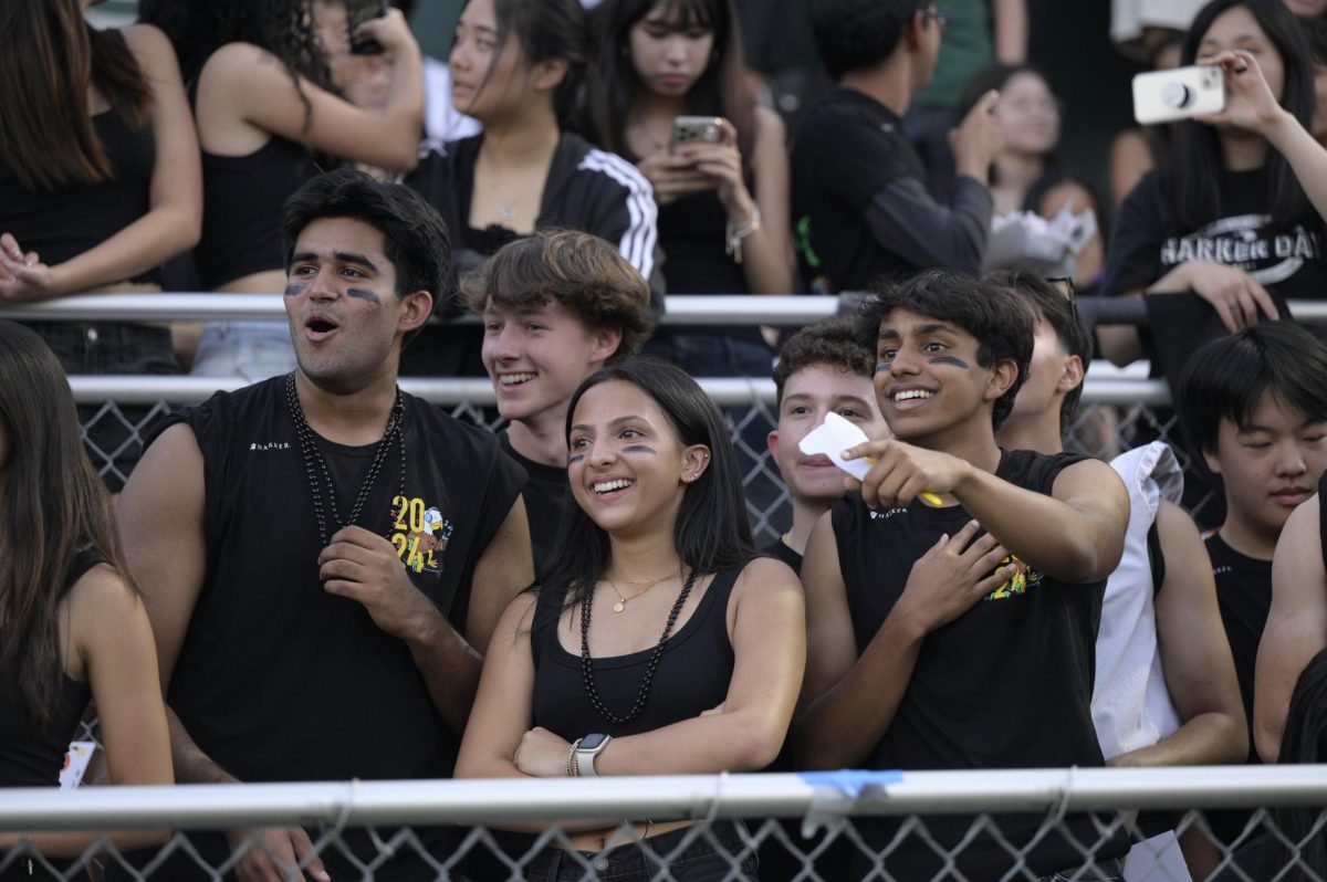 Members of the senior class cheer on the Harker football team. Spectators dressed in black to celebrate the senior class color with the theme “Blackout.”