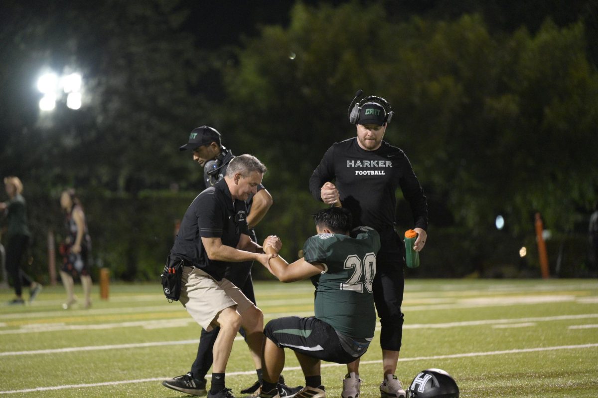 Referees help up Jerry Li (12) after he suffered a knee injured. Jack Ledford(12) has taken over as quarterback.