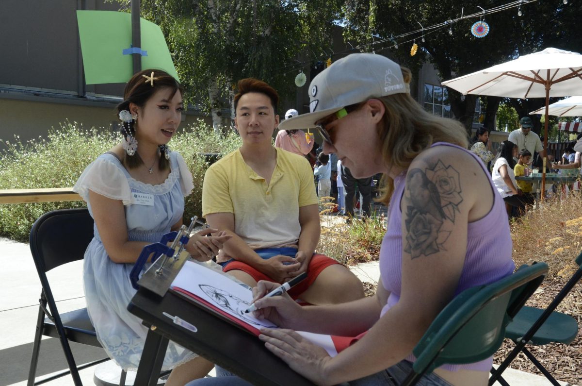 Middle School science teacher Tina Kim poses for a caricature in the quad during Harker Day. The quad also had activities like bouncy houses, an inflatable obstacle course and foosball.