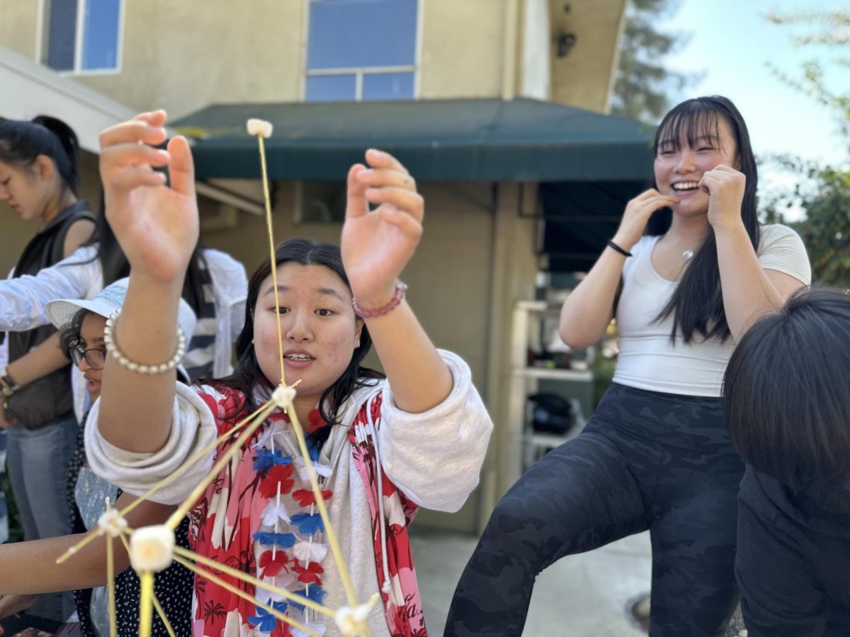 Jia Jia Jiang (11) puts the finishing touches on her groups marshmallow-spaghetti tower during lunch on Monday. Jia Jias team built the highest standing tower in the competition.
