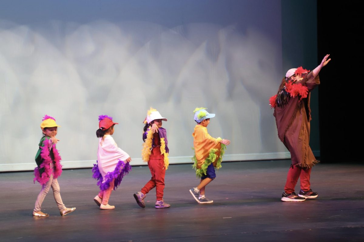 Lower school technical director Danny Dunn leads TK students across the stage as they flap their wings during the Harker Day production on Oct. 11. The TK students dressed as birds from the Galápagos Islands.