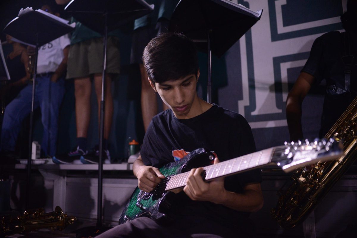 Orion Ghai (10) strums his guitar as part of the Pep Band. Pep Band opened the game and continued to play throughout.