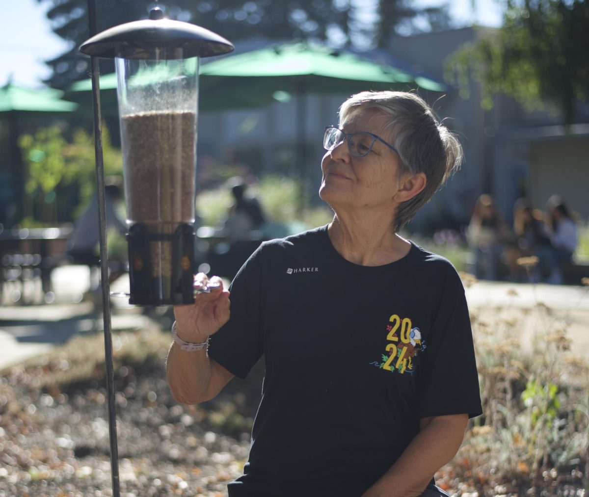 Upper school computer science teacher Susan King inspects a bird-feeder in the quad. Ms. King began bird watching in 2020, fascinated by their flight and plumage patterns.