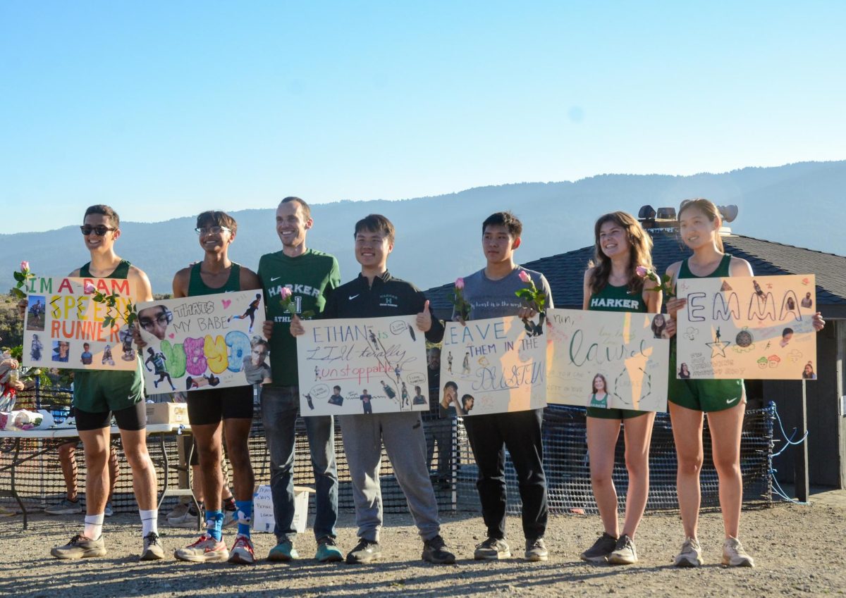 The cross-country seniors pose with upper school cross-country head coach Kevin Oliver, holding up posters decorated by the team. When we’re at meets, there’s a great team vibe where everyone is very supportive of each other, senior Emma Gao said.
