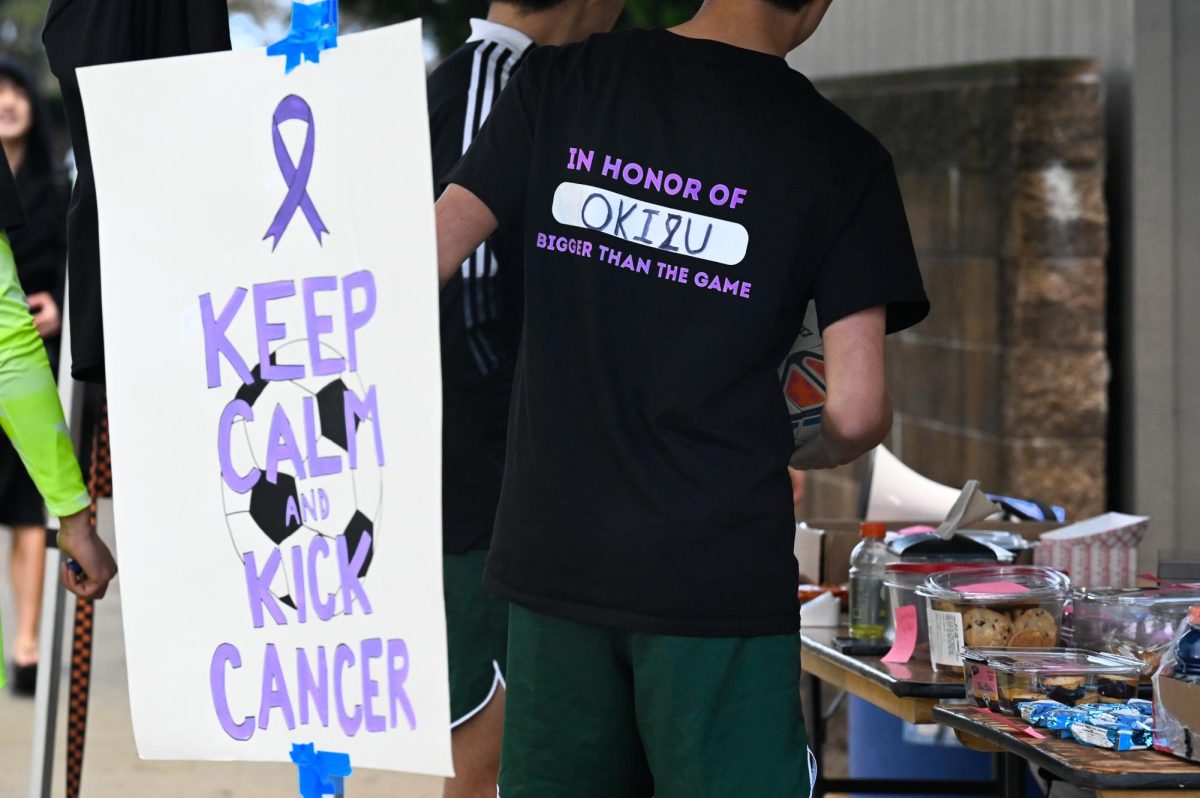 A varsity boys soccer player checks in with the baked goods table. Community members donned Kicks Against Cancer merchandise in support of the cause. 