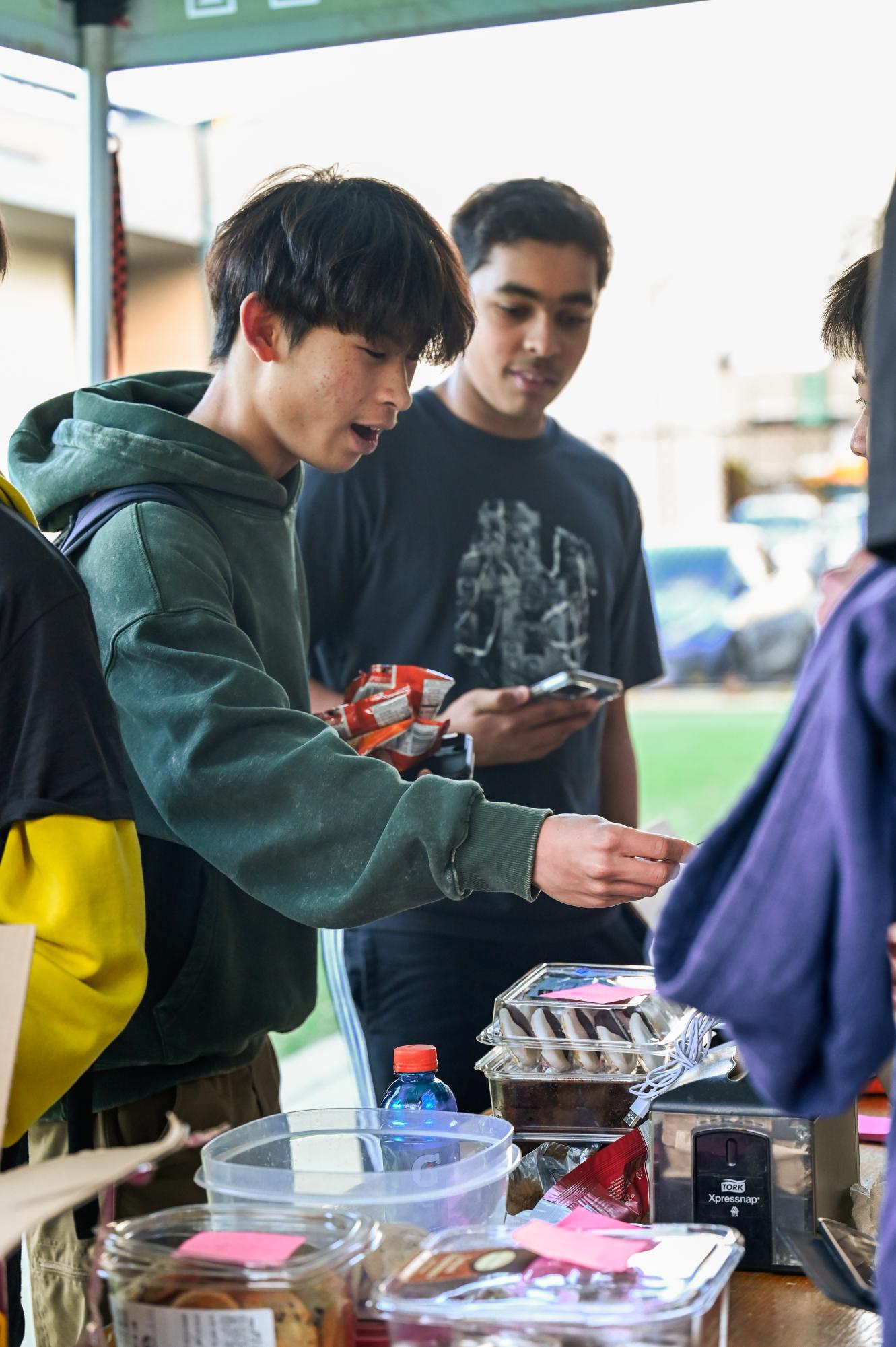 Stanley Chen (10) purchases baked goods at the Kicks Against Cancer bake sale. The varsity soccer teams sold baked goods during long lunches from Jan. 29 to Feb. 2.