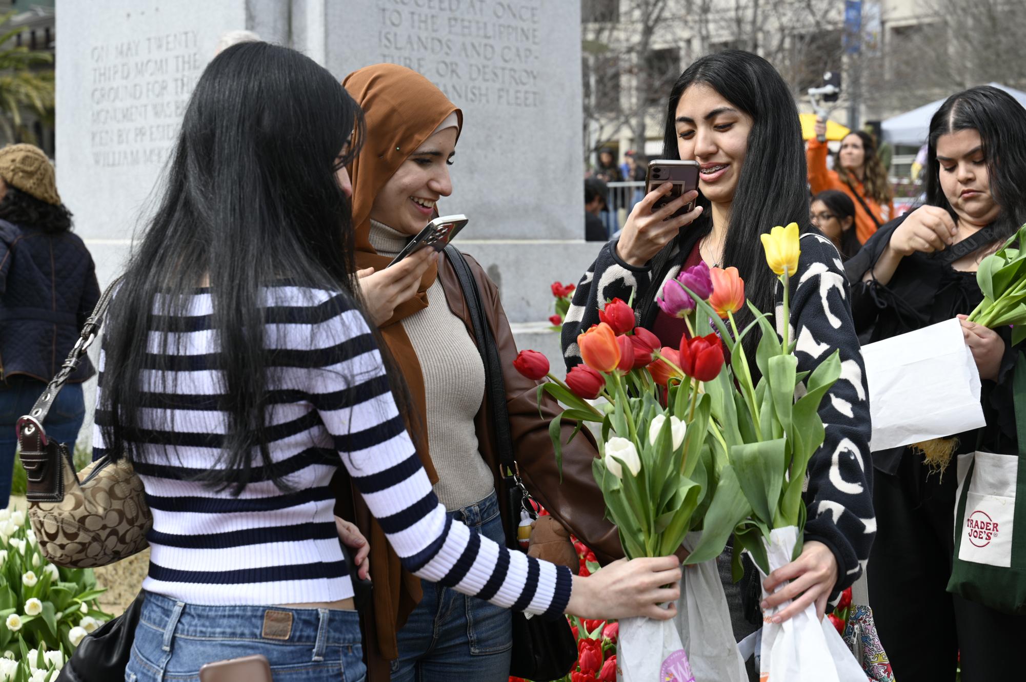 Three friends take photos of their bouquets. This year marked the sixth annual Tulip Day in San Francisco. 