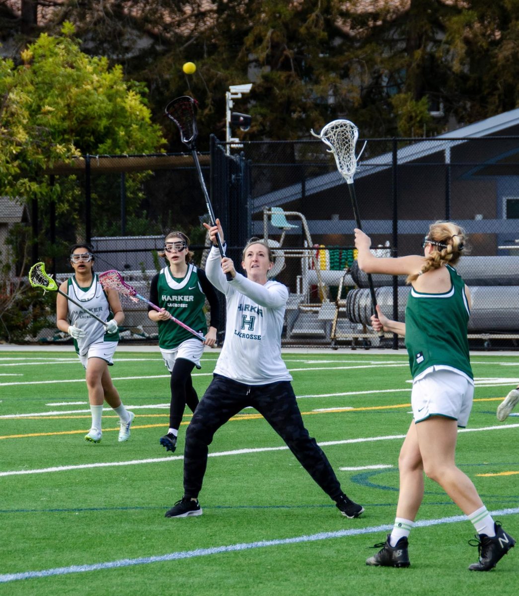 Head coach Lauren Brown attempts to block a pass during a lacrosse team practice. She stepped in during a practice drill acting as a defender.