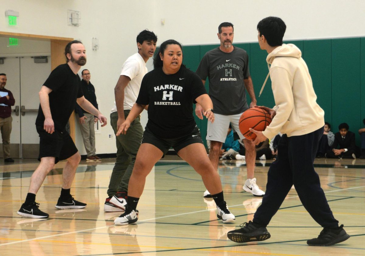 Academic counselor Jonah Alves guards an opponent in a teacher-student basketball match during the school meeting on Feb. 22. The faculty team Alves was a member of, Below the Rim, placed third overall. 