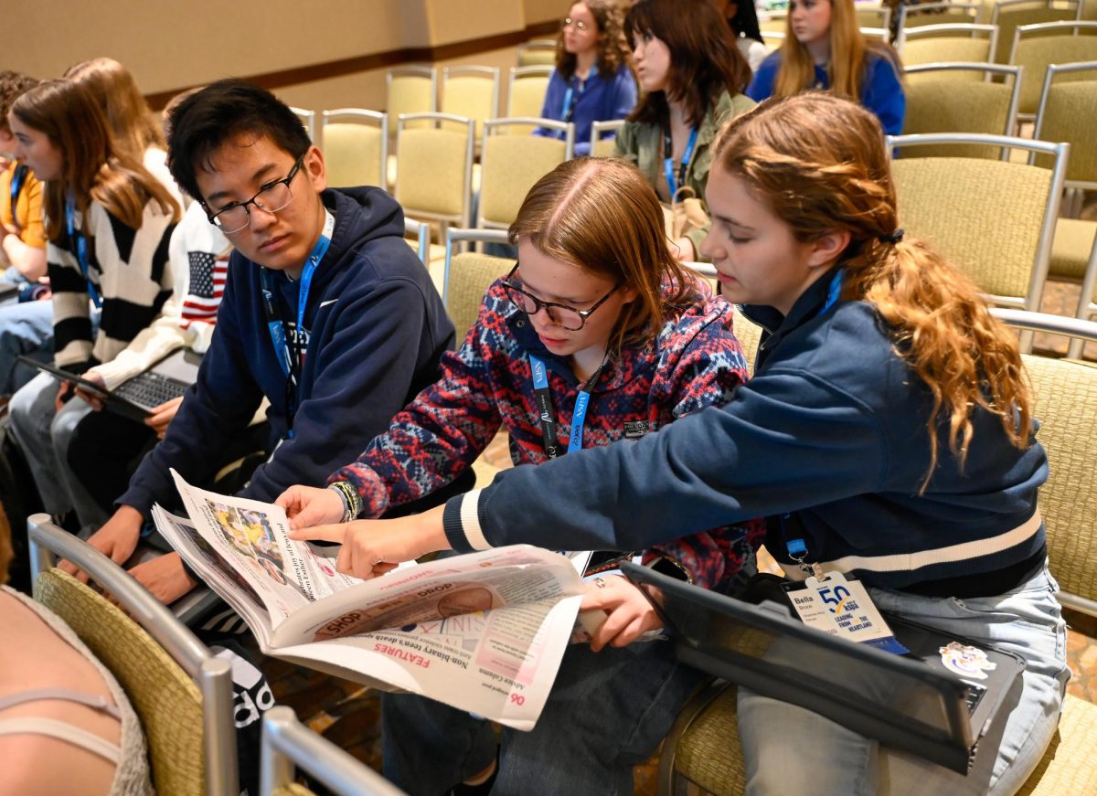 Students from the Shawnee Mission School district in Kansas review a page in a Winged Post issue. Harker Aquila staff members passed out copies of the newspaper for audience members to look over.