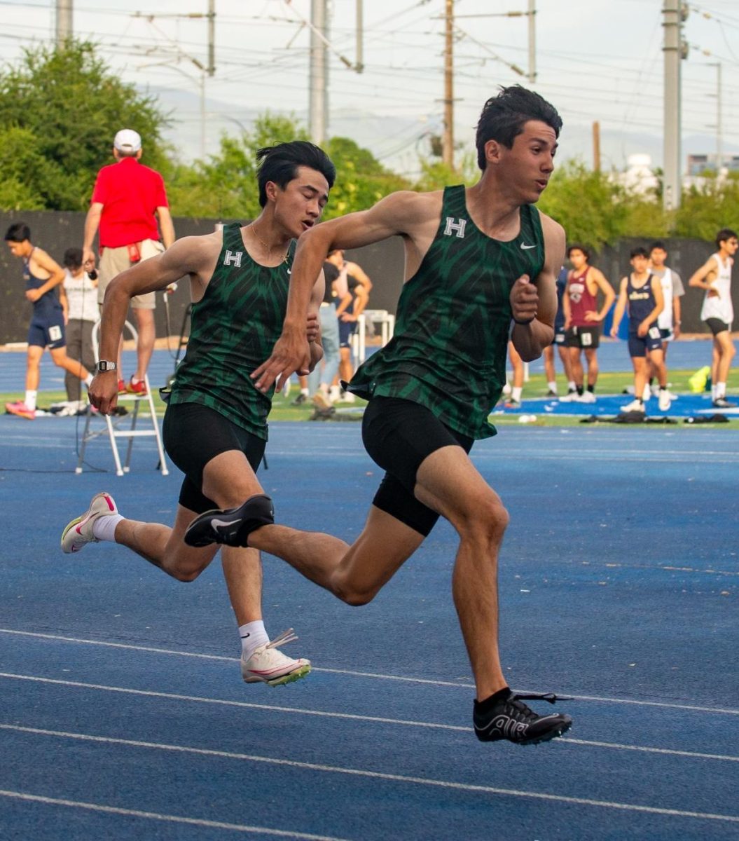 Brady Tse (10) and Micheal Chang (12) pump their arms as they push themselves towards the finish line in the mens 100-meter race. Both sprinters set personal records during this event.