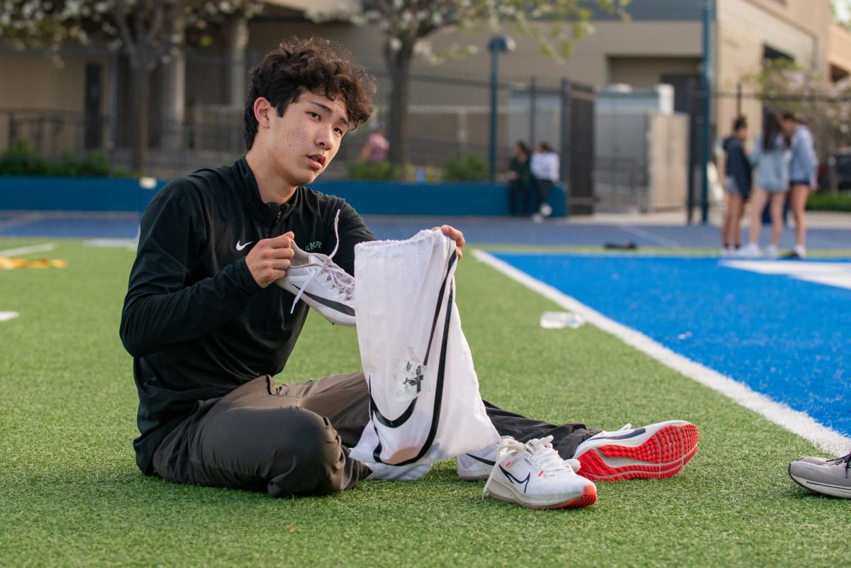 Frosh Kai Nishimura unpacks his running shoes into his bag before the meet. Kai ran a personal record in the 100-meter dash with a time of 11.70. 