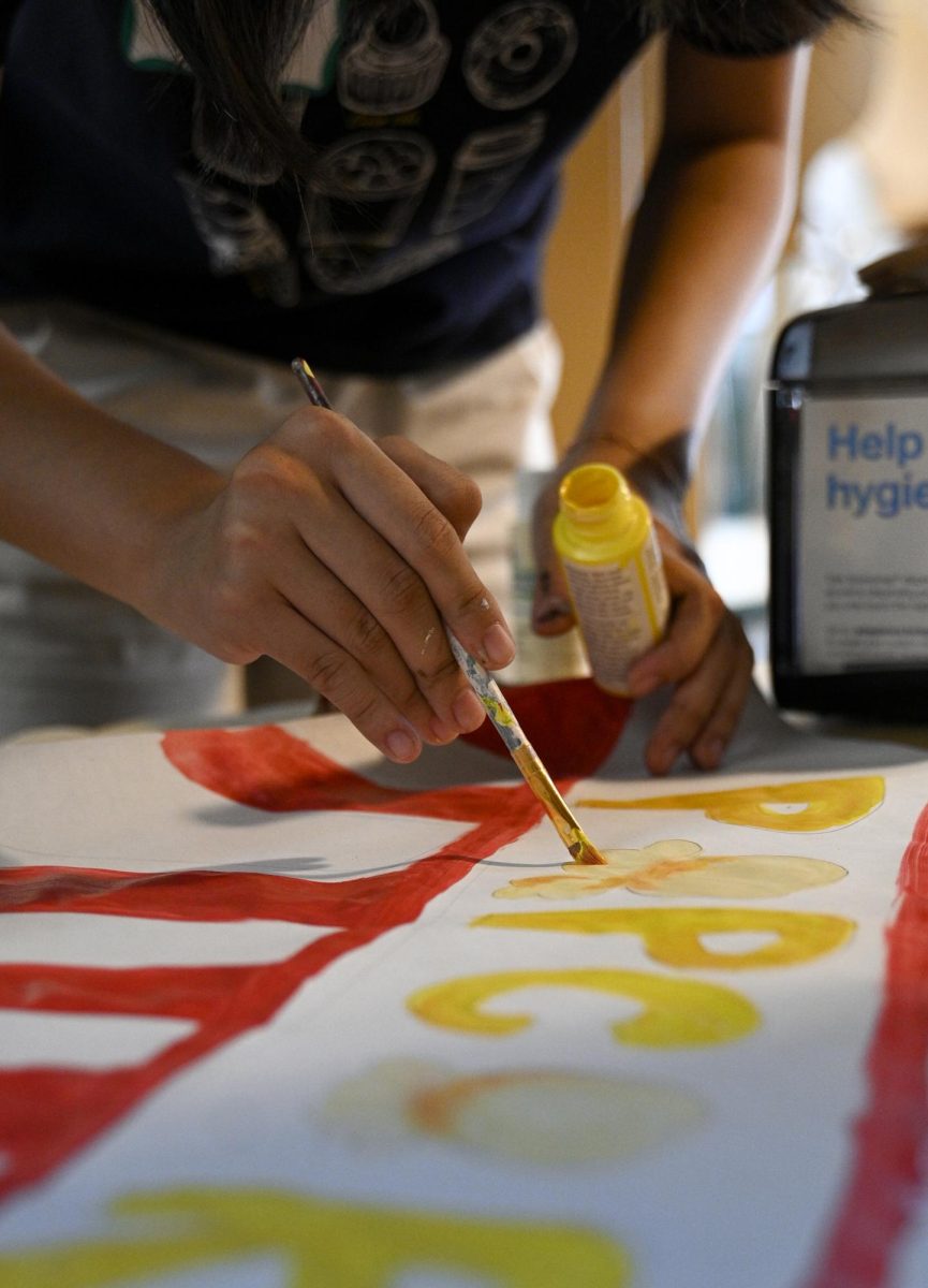 Leana Zhou (11) adds finishing touches to her poster. HSLT prepared posters for Spirit Kickoff, which will be held Sept. 26. 