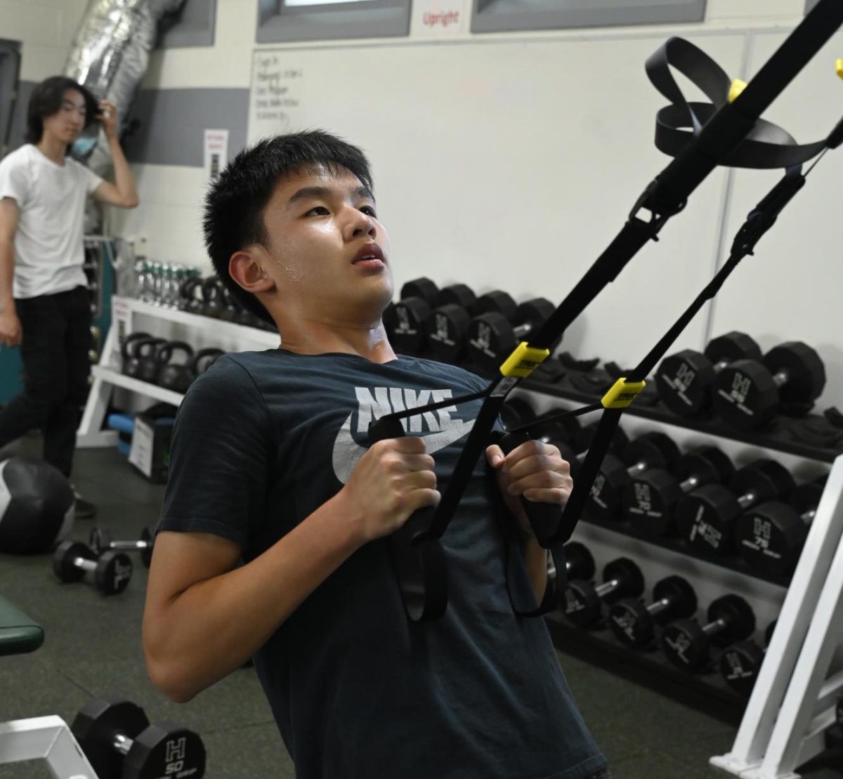 Michael Jin (9) uses TRX during his  workout in the weight room. For high school students, fitness generally comes in the form of weight lifting, cardio exercises and the classic squats, crunches and pushups.