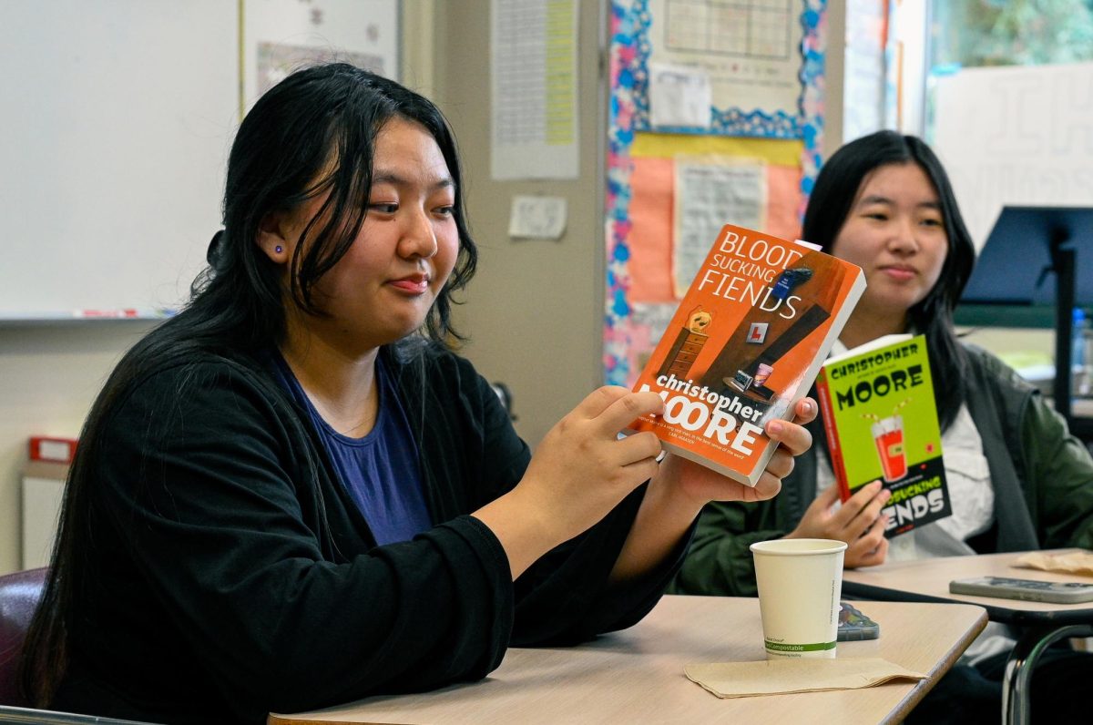 Senior Claire Perng examines the cover of her ReCreate Reading book. Sponsored by upper school math department chair Anthony Silk, the vampire-themed novel attracted several students. 