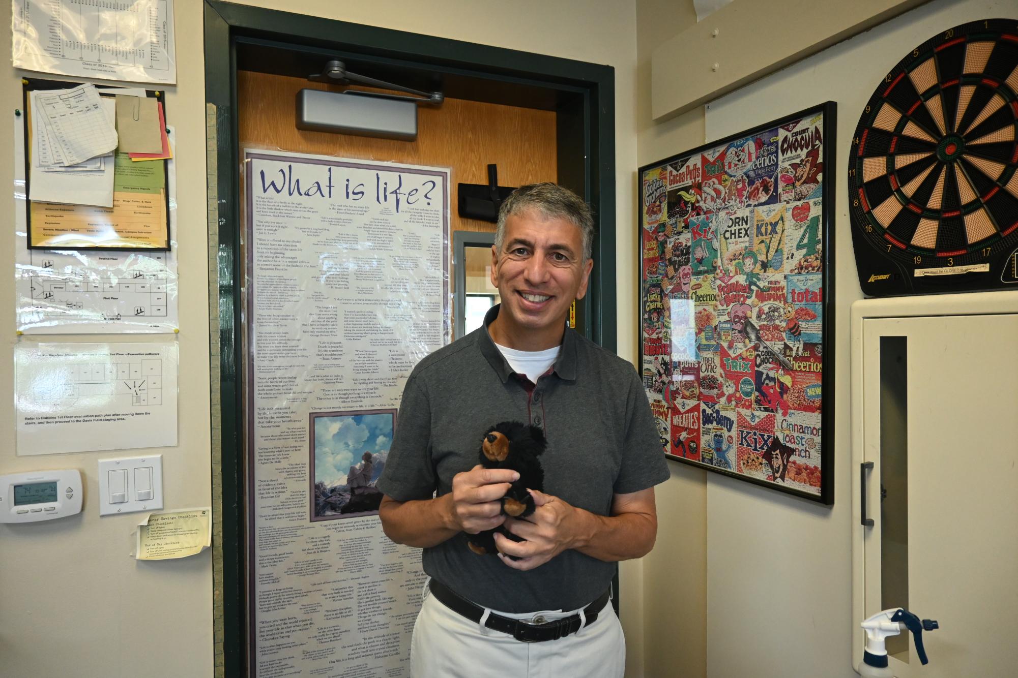 Anthony Silk poses with his beloved bear, Bear Minimum. The stuffed toy serves as a source of comfort to his students. 