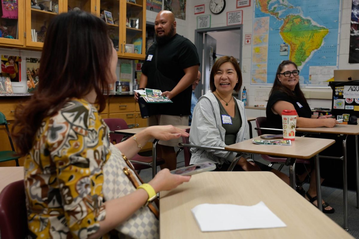 Parents banter during the passing period before Moss's class. Throughout the day, they amassed pamphlets, worksheets and syllabi from teachers. 