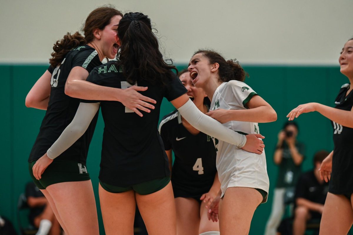 Libero Norah Mehanna (12) congratulates fellow members of the varsity girls volleyball team after they win a point. The Eagles crushed Castilleja in three sets on Sept. 24.