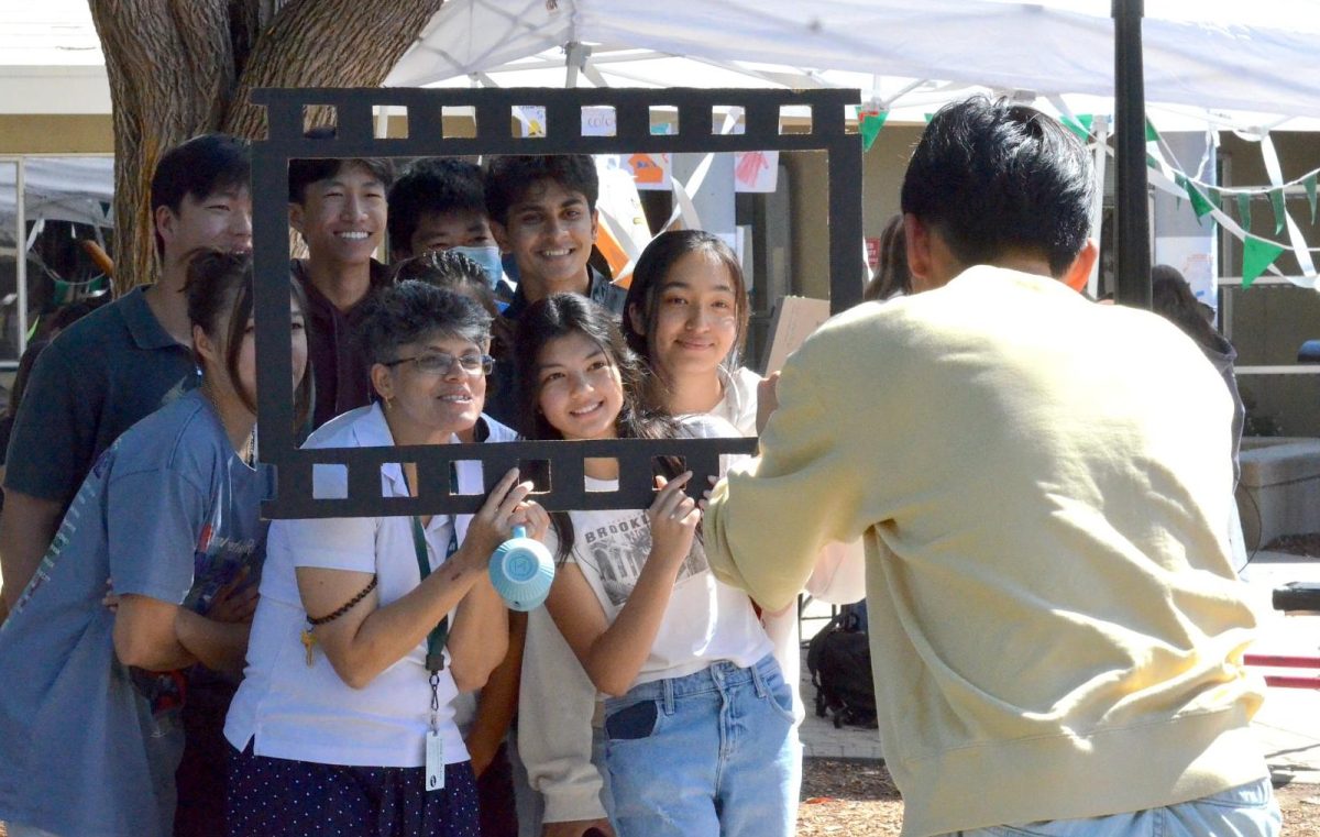 Kairui Sun (11) takes a photo of math teacher Caren Furtado and a group of her students. HSLT co-community event secretaries walked around campus during lunch with a mock film frame, inviting students to pose for pictures.