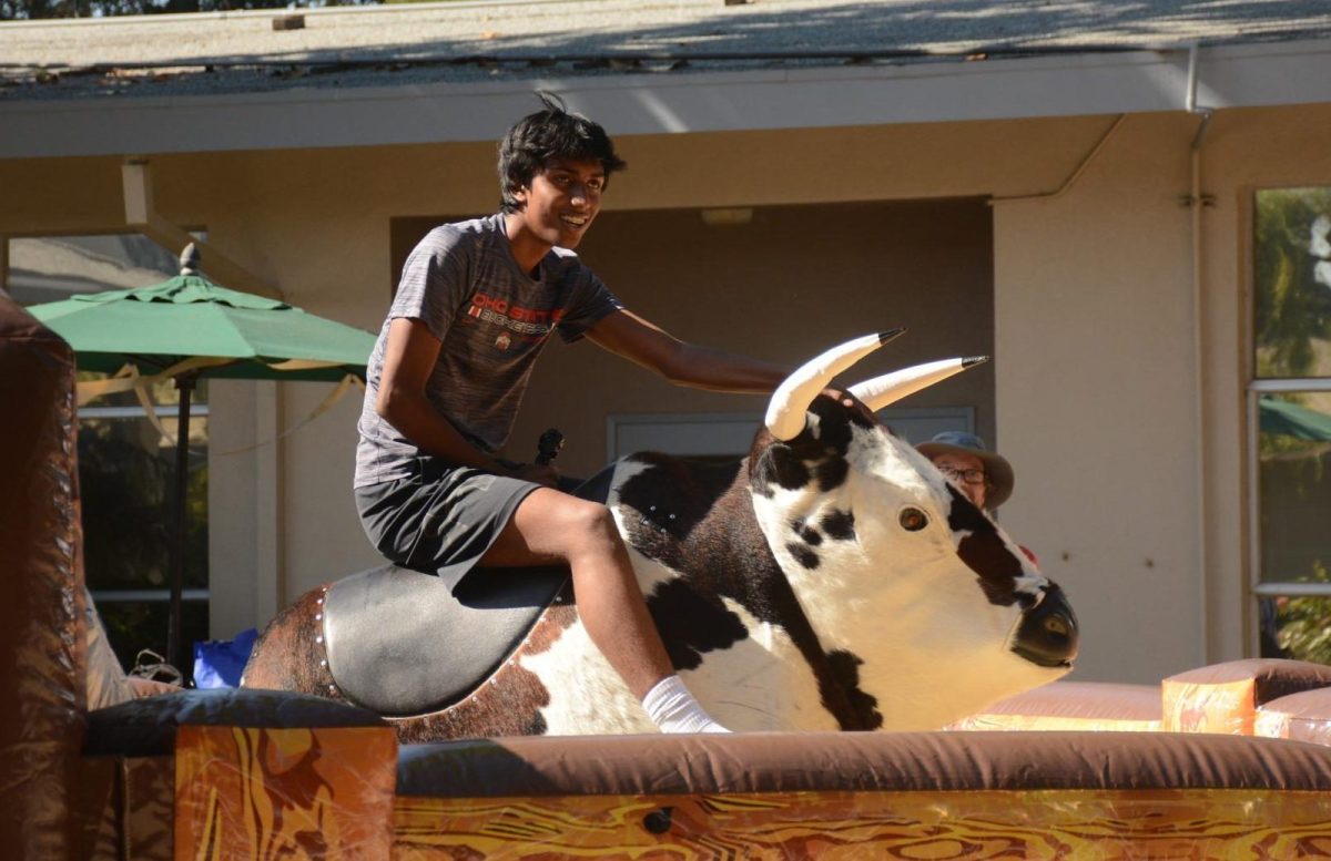 Rishaan Thoppay (11) braces for a ride on the mechanical bull. Attendees hung on to the bull for as long as possible while it bucked and swayed wildly.