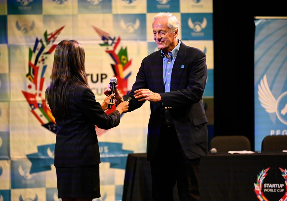 Anya Mukherjee (10) hands the microphone of to Chief Evangelist of Pegasus Tech Ventures Bill Reichert. The Startup World Cup planning team also invited the founder and CEO of Poshmark Manish Chandra, who spoke as a keynote speaker.