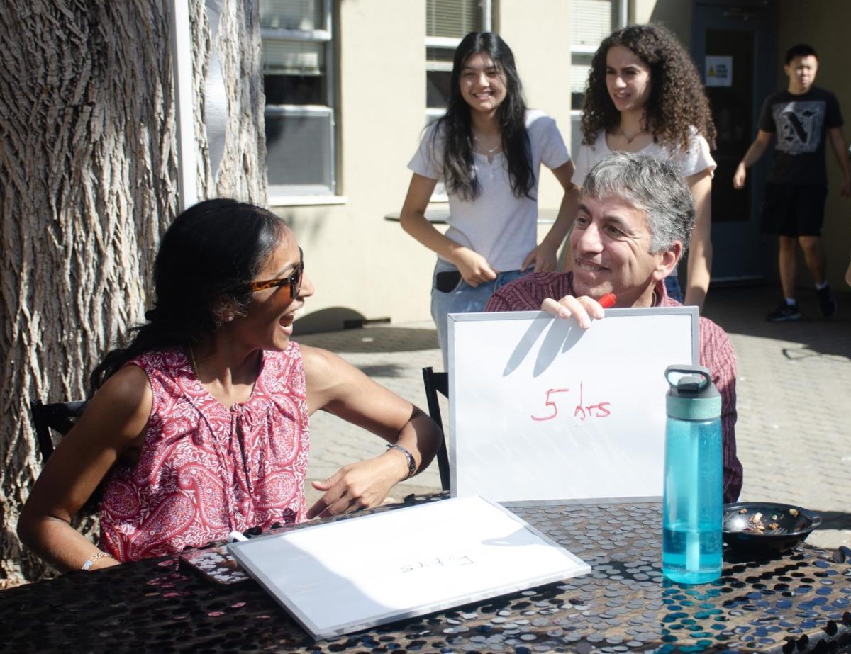 Mathematics department chair Anthony Silk holds up his whiteboard when asked how many hours he prepares for classes. Silk and math teacher Anu Aiyer competed against history teachers James Tate and Jonathan Rim in the Newlyfriend game.