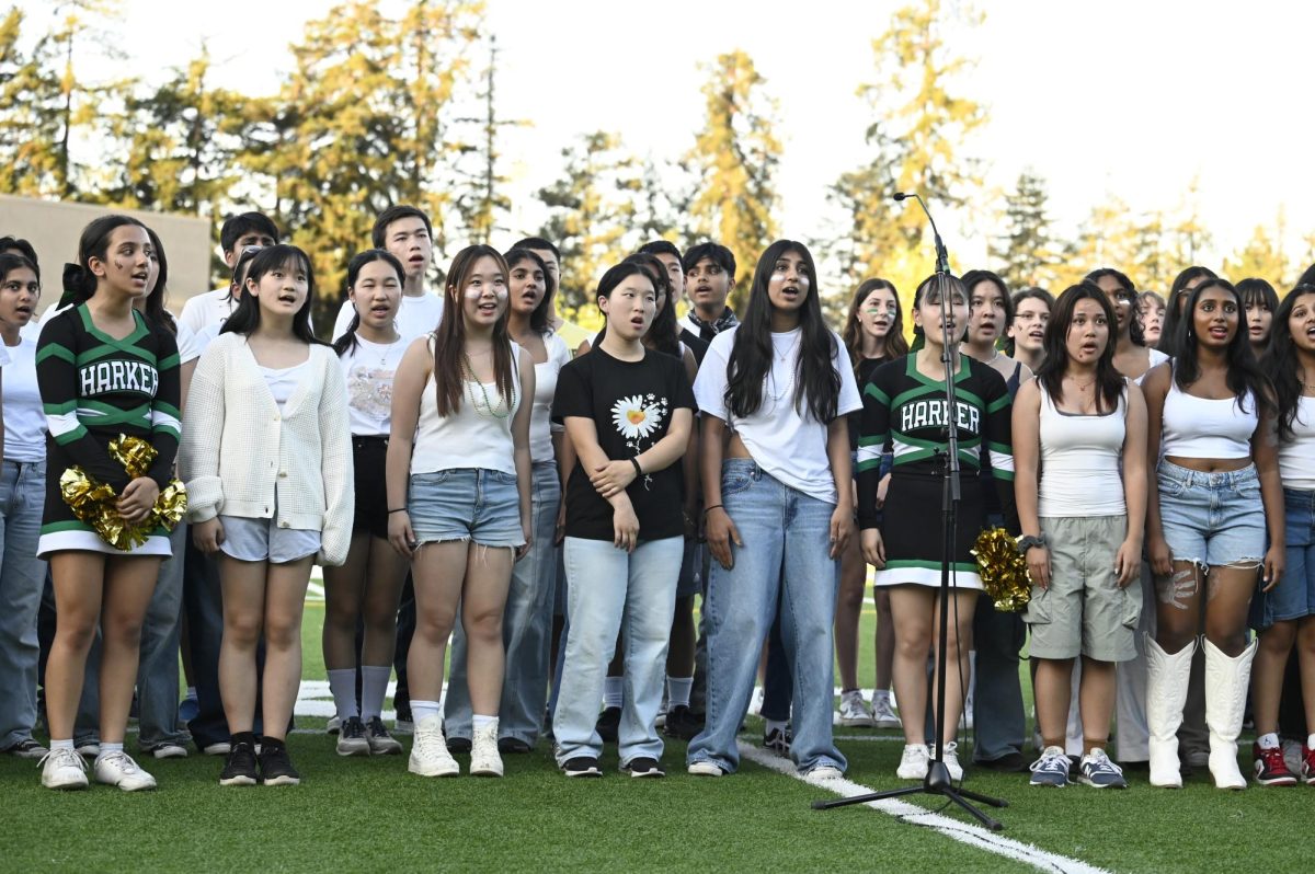 The all-school choir sings the national anthem. Football players and audience members stood while they sang. 