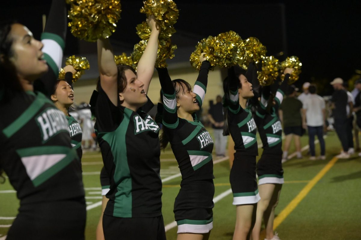 Ollie Masoni (11) brings the pom-poms up with the varsity cheerleading team on the sidelines. The team led cheers like "Color Shout."