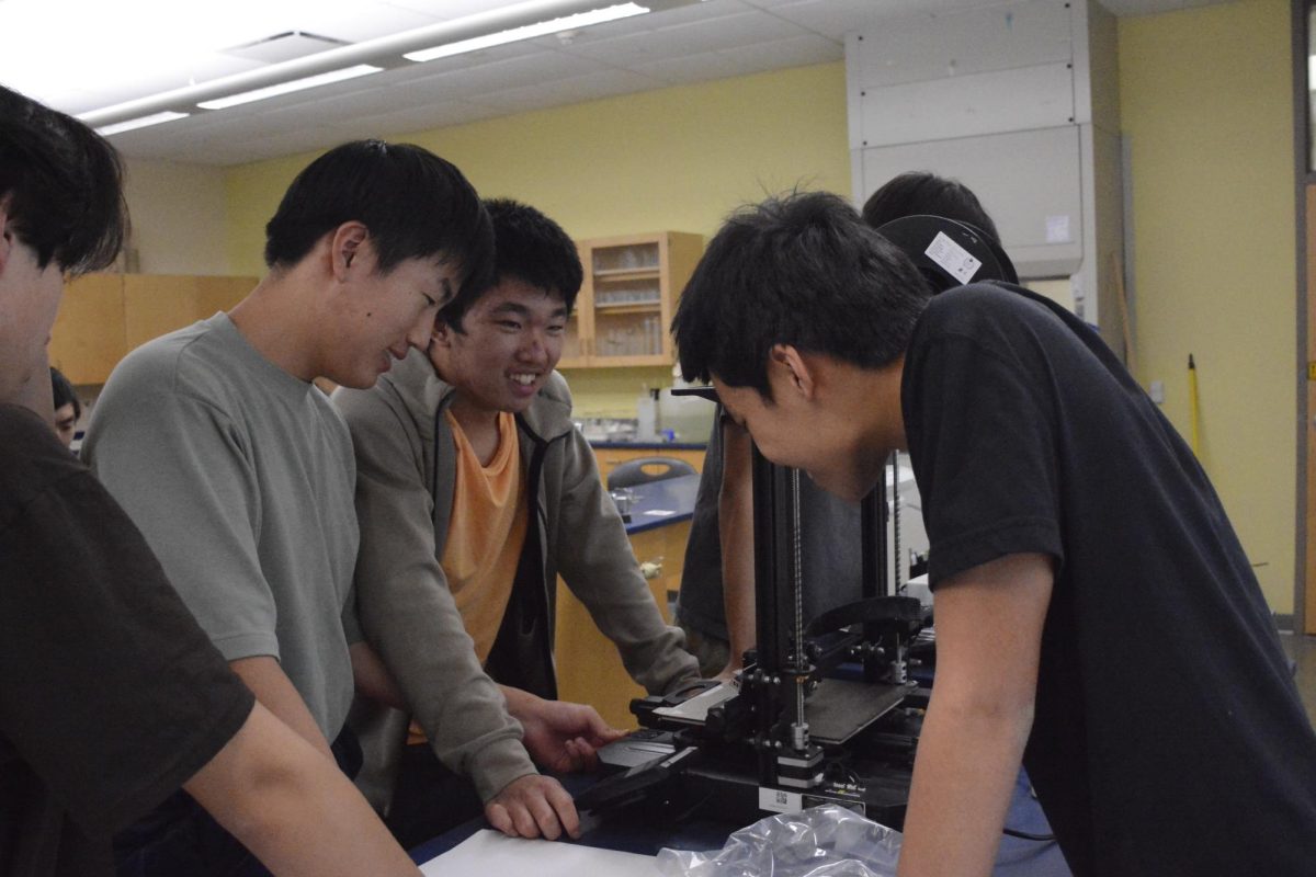 3D Printing and Design Club president Evan Zhang (11) smiles as he explains the functionality of the 3D printer to members. To prepare the printer, users needed to preheat the print bed and load the model’s computer-aided design (CAD) file.