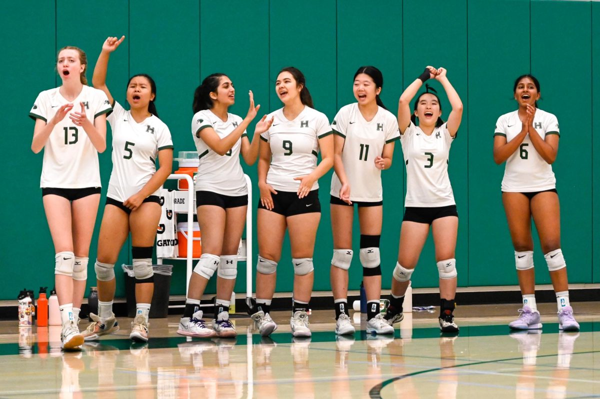 Varsity girls volleyball players cheer their teammates on after they scored a point. Invigorating chants uplift the players’ mentalities, keeping the players focused on the game.