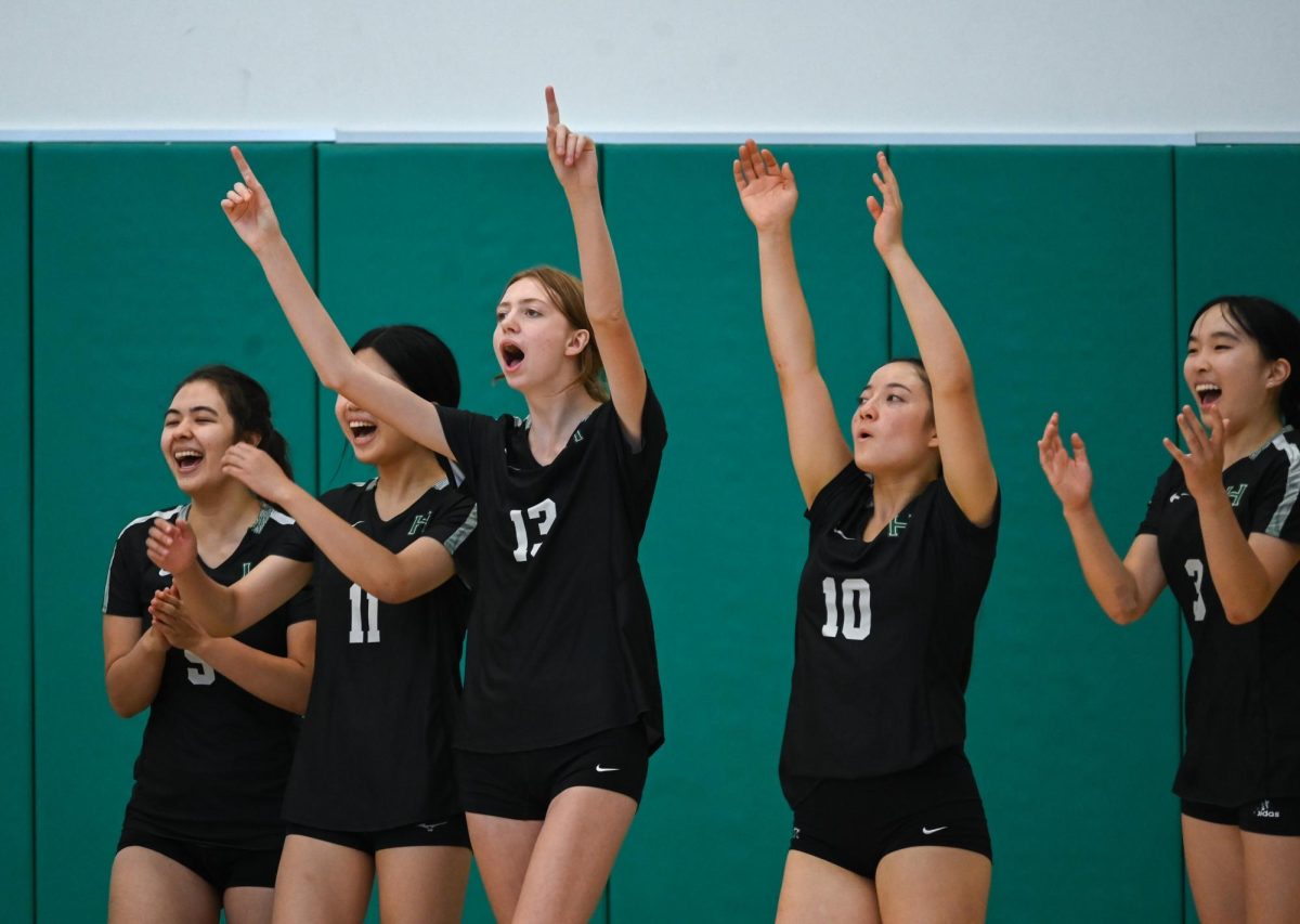 Varsity girls volleyball players Eden Kelly (11) and Aline Grinspan (11) throw their hands into the air as they cheer for an ace. Points won off aces frequently garner their own chants. 