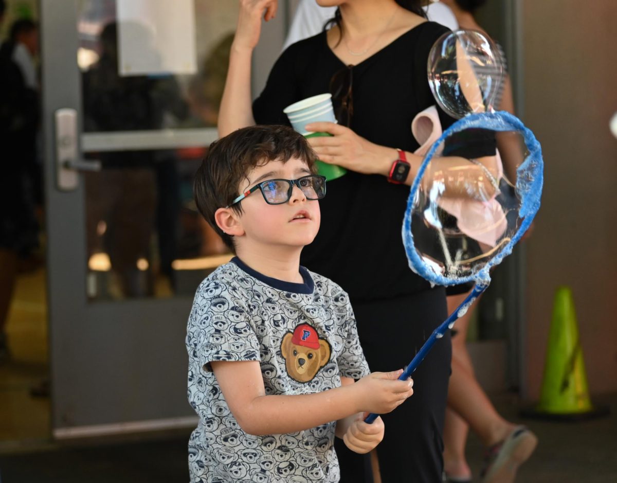 A Harker Day attendee plays at the bubbles station in the Quad. Students could play with a variety of bubble wands and nets.