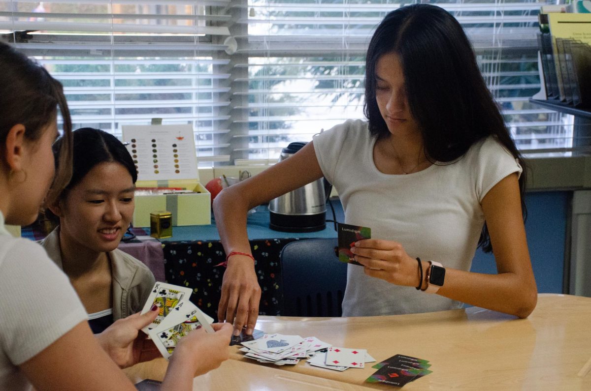 Aanya Sharma (10) plays a card game with her friends during a break in English class. English teacher Beth Wahl's class also holds legos and a mini basketball hoop for students to use.