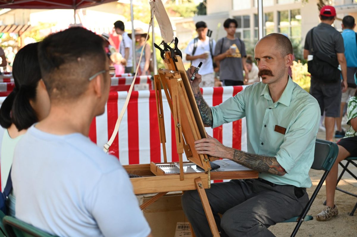 A caricature artist draws a couple's portrait in the Quad. The Quad held multiple other activities, like carnival games and student-run booths. 