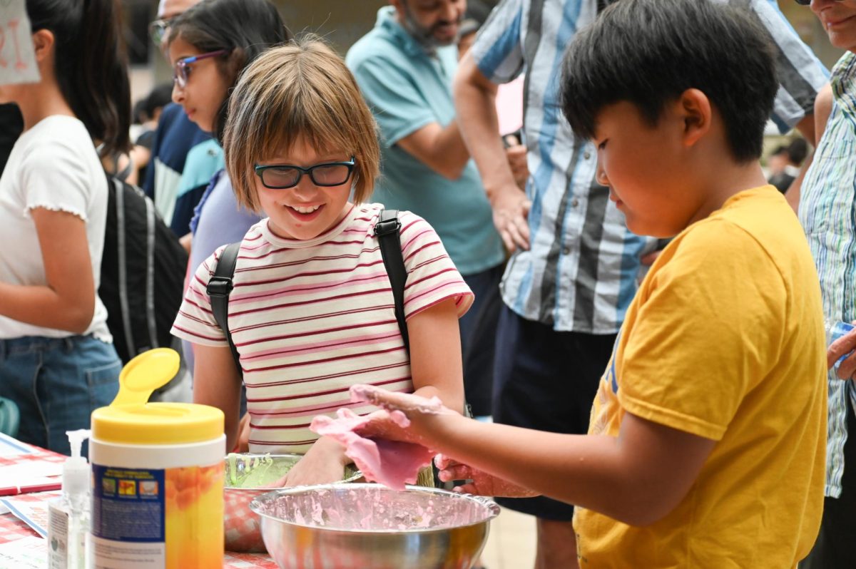 Two Harker Day attendees play with slime at a booth in Nichols Hall. Nichols featured a variety of different booths to engage with students and parents. 