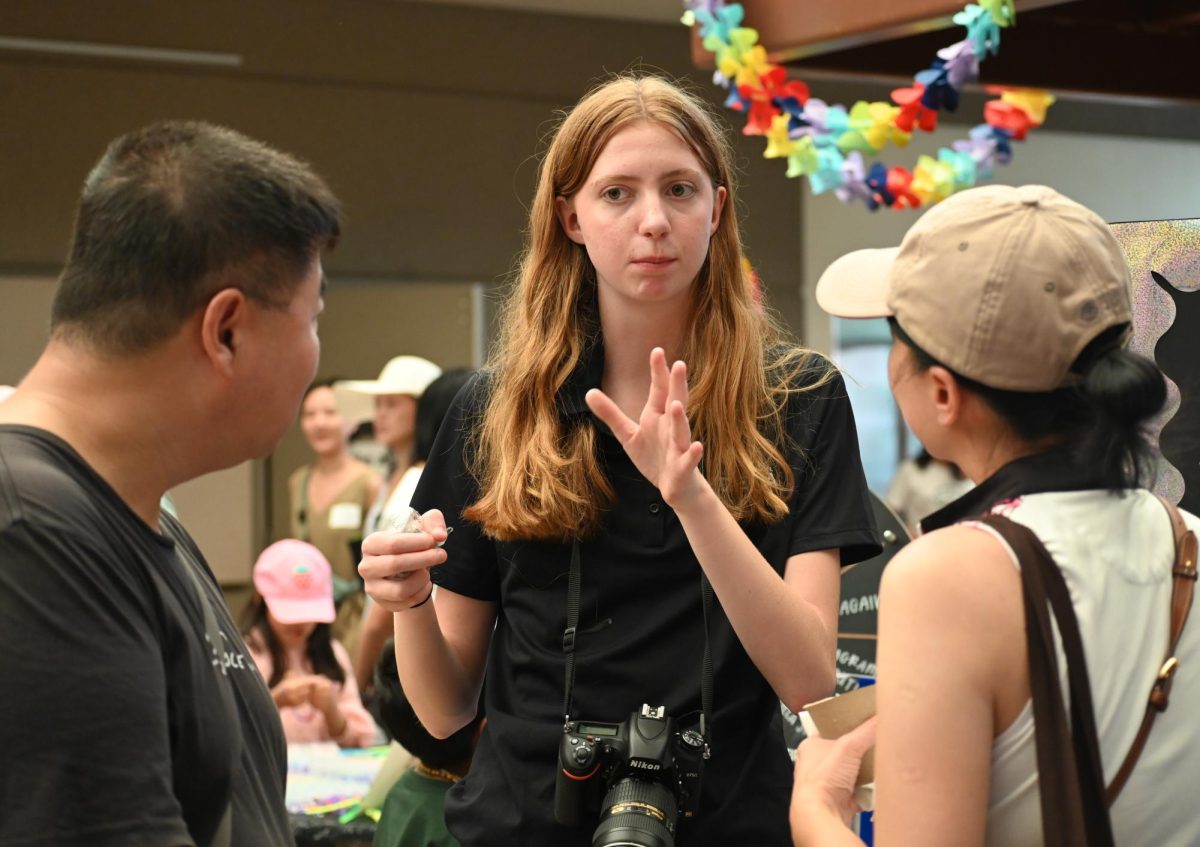 Junior Eden Kelly talks to parents at the DECA booth on Saturday. DECA was one of dozens of other clubs that was displayed in Nichols Hall. 