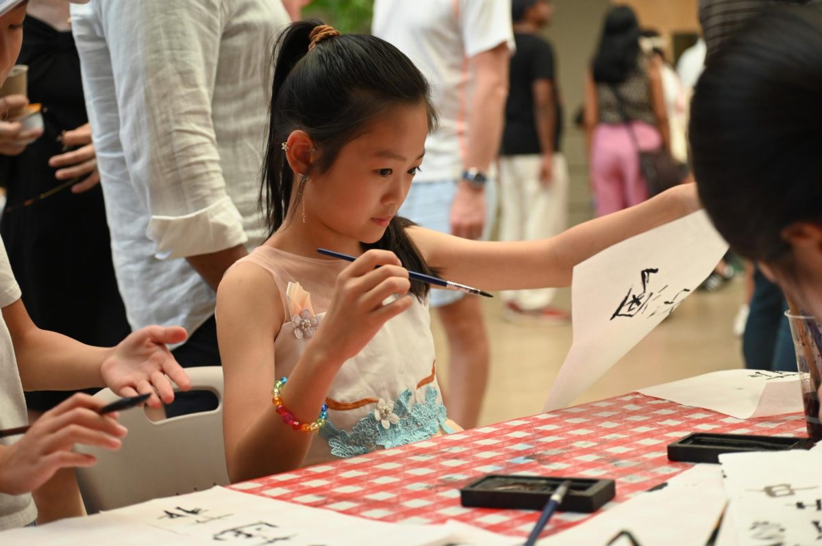 A Harker Day attendee draws calligraphy at the Japanese and Chinese National Honor Society's booths. The Chinese National Honor Society held a Mid-Autumn Festival celebration with food an activities last Thursday outside Manzanita Hall. 