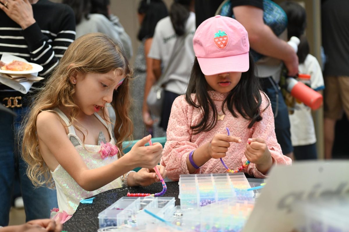 Two Harker Day attendees make bracelets using beads and pipe cleaners. Harker Day invited students from all grade levels, as well as staff, alumni and parents. 