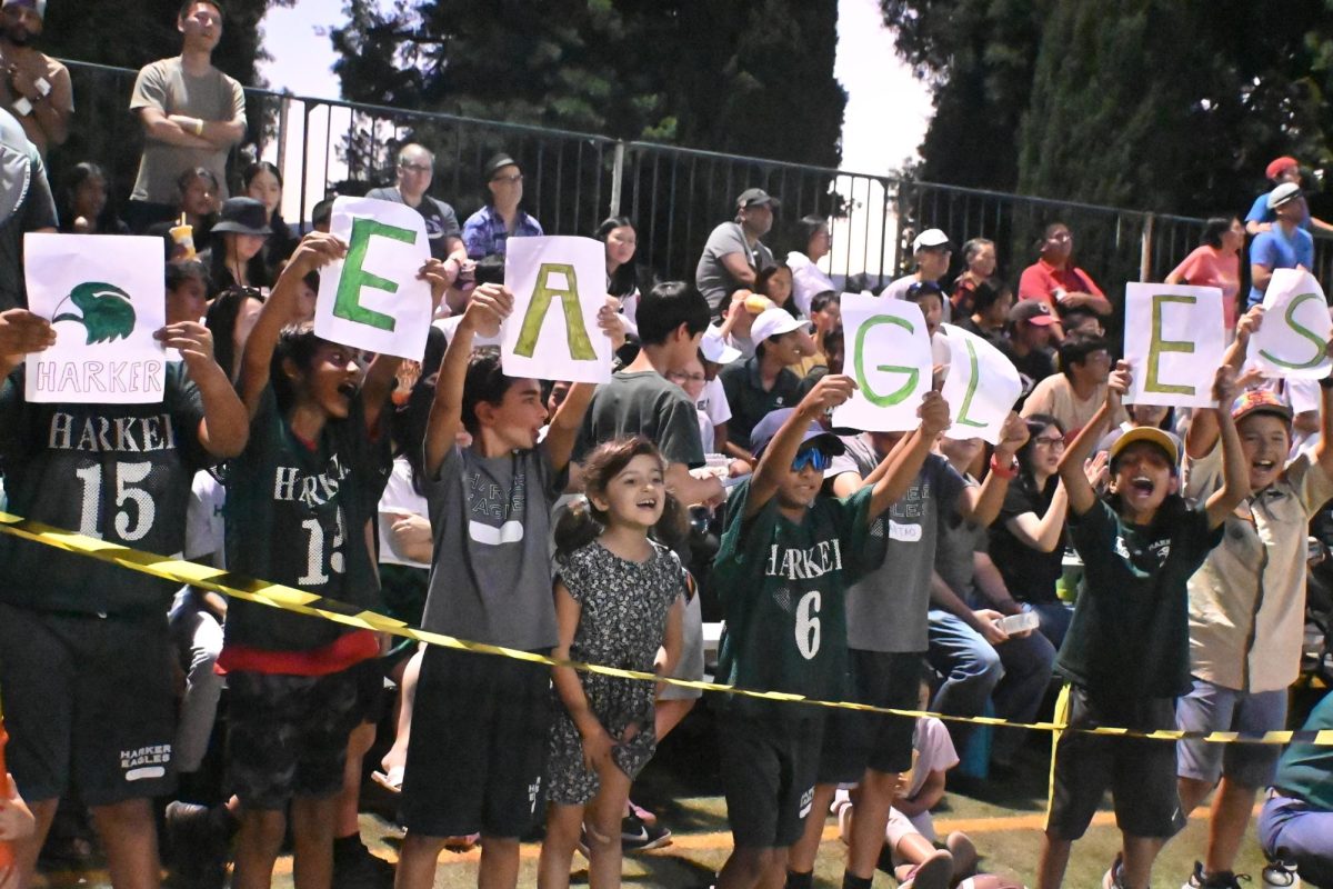 Lower school flag football team members hold up handmade signs spelling out "EAGLES." Students from all grades packed the audience to support Harker