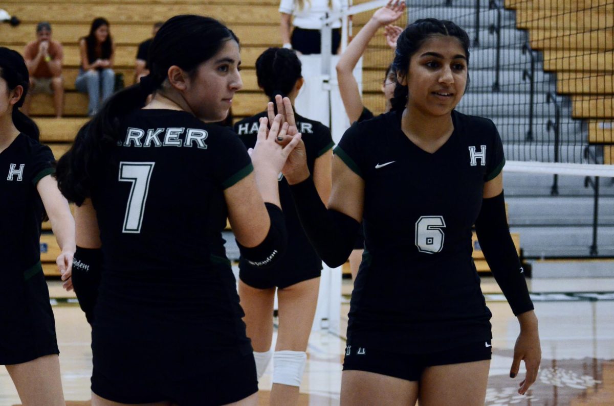 Setter Lily Ahluwalia (9) and opposite Aarya Vaidya (9) high five after winning a point. The junior varsity girls volleyball team started the first set with eight consecutive points against Castilleja. 